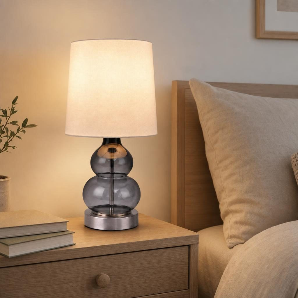 Lampe Hyōtan en verre gris fumé allumée sur une table de chevet en chêne