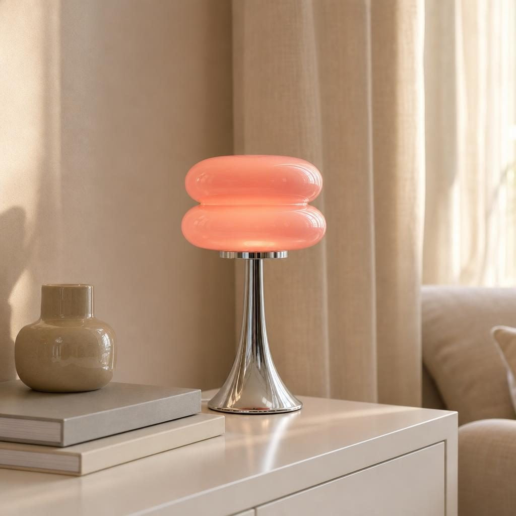 Lampe Macaron à abat-jour rose allumée sur un buffet blanc dans un salon lumineux