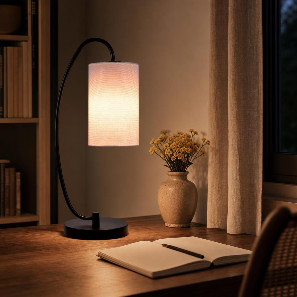 Lampe Magari allumée sur un bureau en noyer à côté d'un carnet ouvert