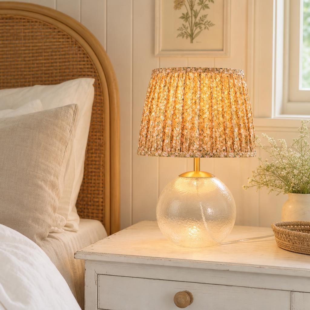 Lampe Nobara allumée sur une table de chevet blanche dans une chambre