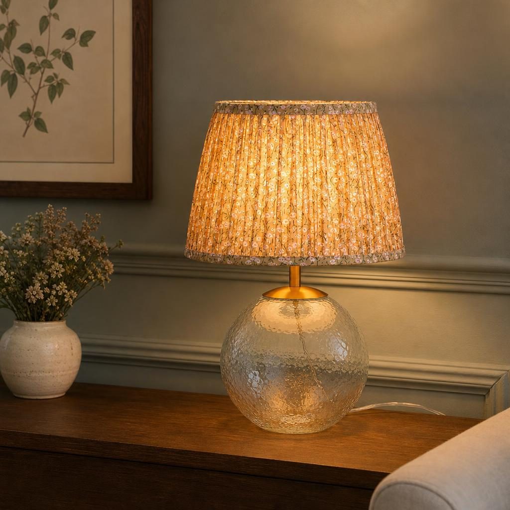 Lampe Nobara allumée sur une console en bois devant un lambris vert sauge