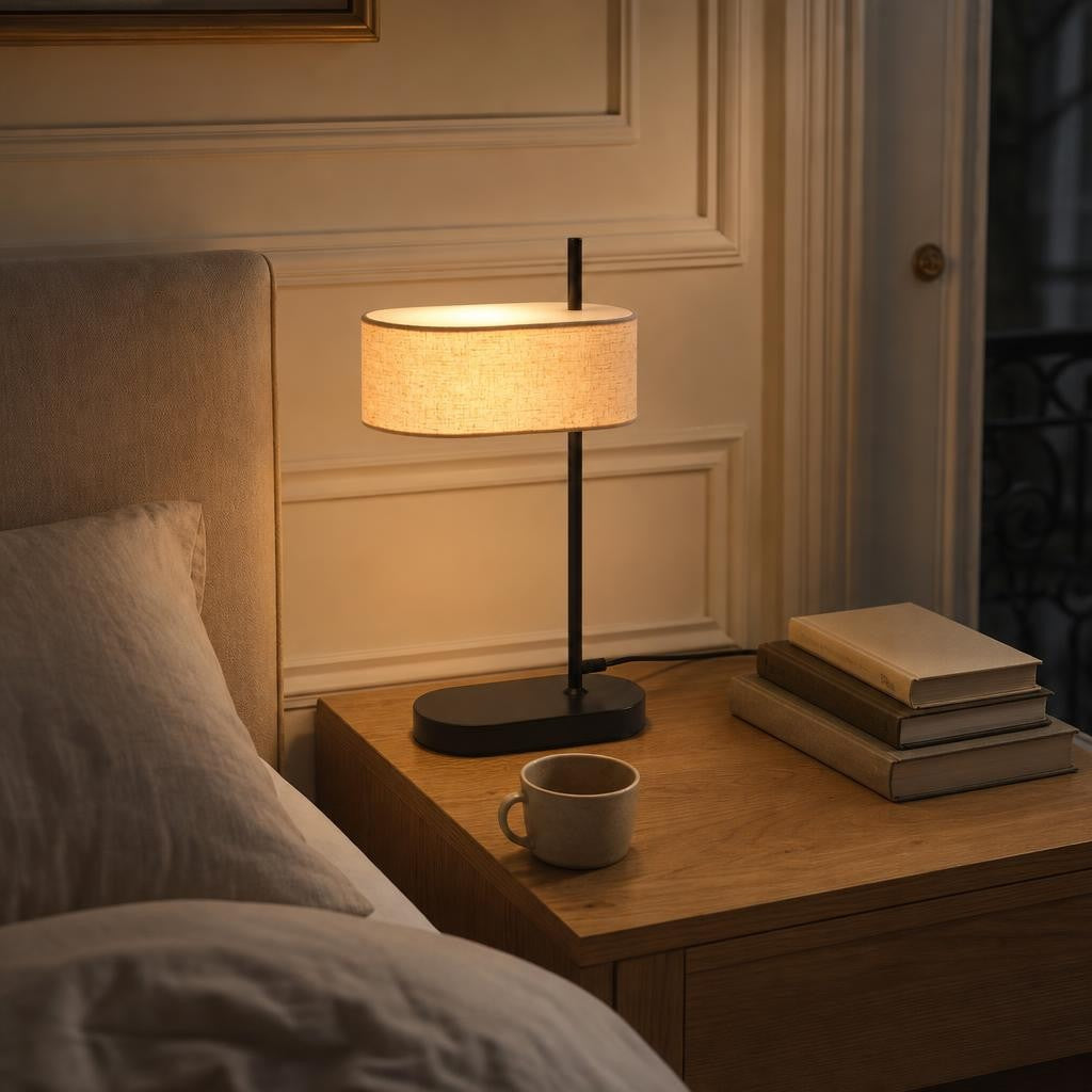 Lampe Shiori allumée sur une table de chevet en chêne avec des livres