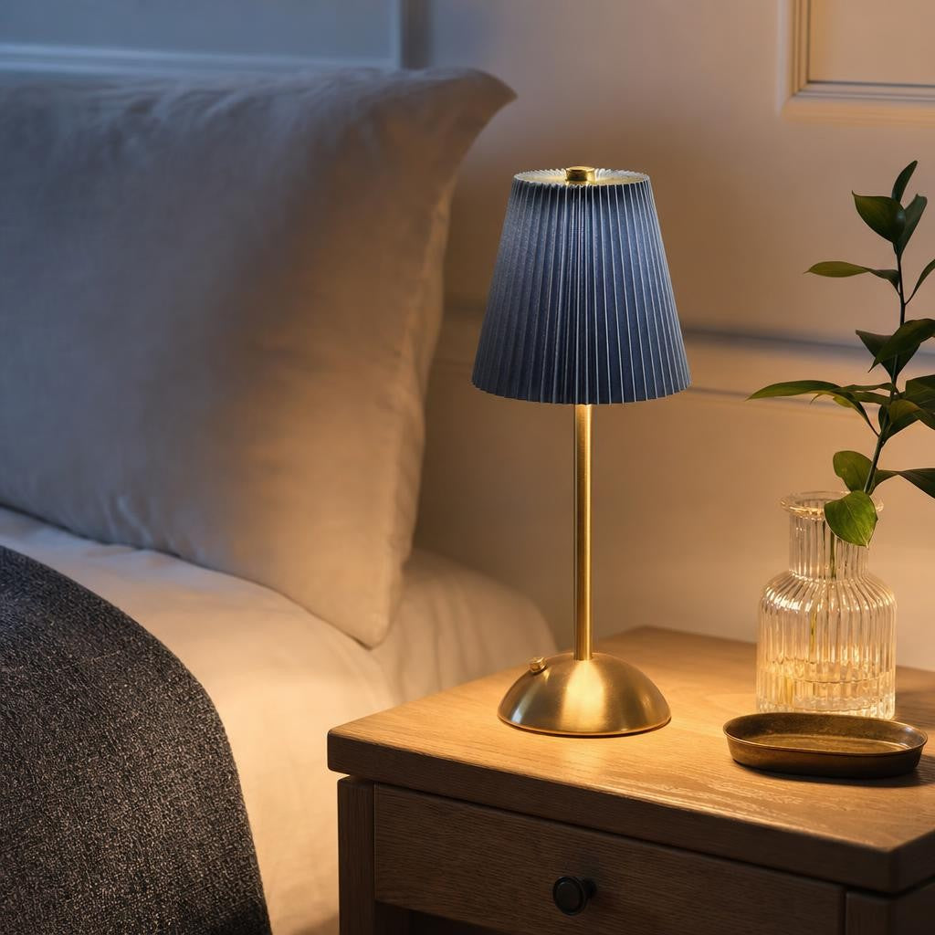 Lampe Mika bleu marine allumée sur une table de chevet